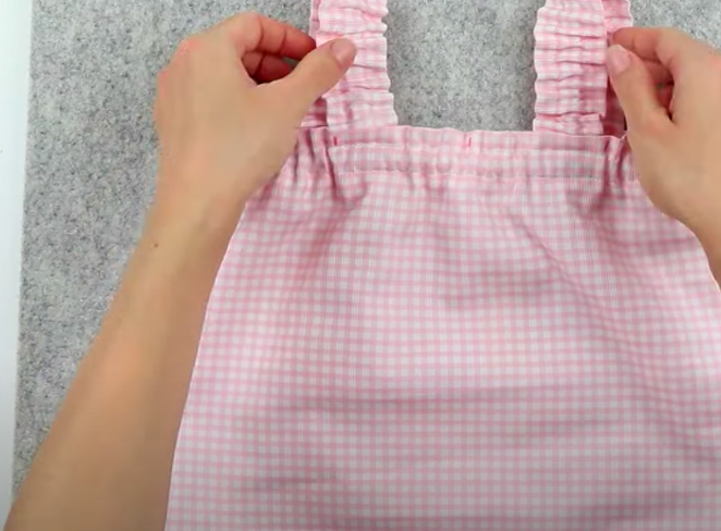 realización de costura de tiras de tela en tela de blusa para niña